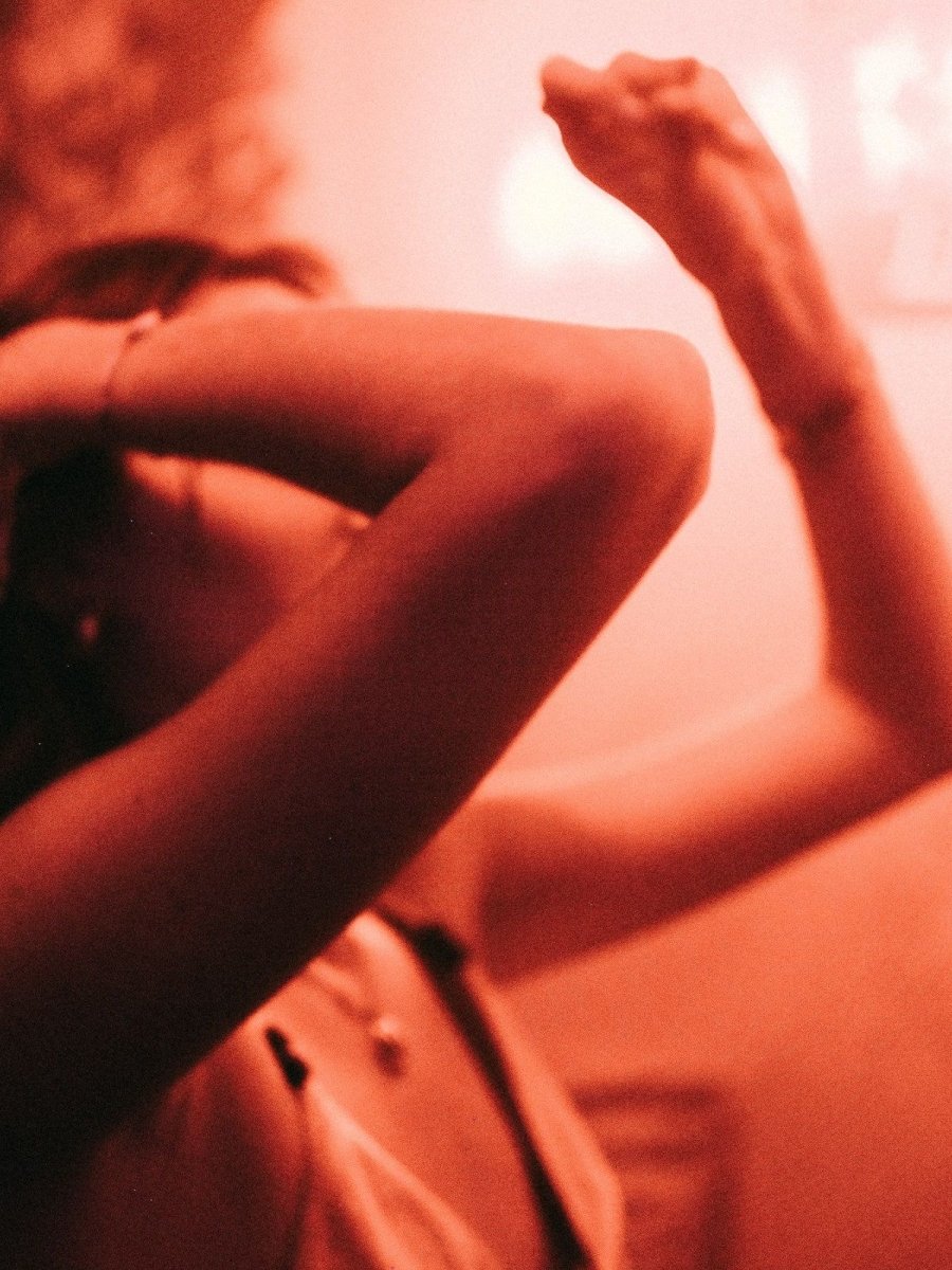 Zwei Körper bewegen sich nah beieinander in warmem, rötlichem Licht