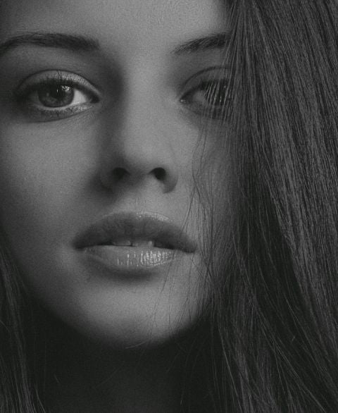 Nahaufnahme eines Frauengesichts in Schwarzweiß, der Blick wirkt ruhig und nachdenklich
