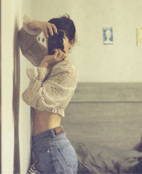 Frau fotografiert sich selbst im Spiegel, das Bild wirkt ruhig und intim